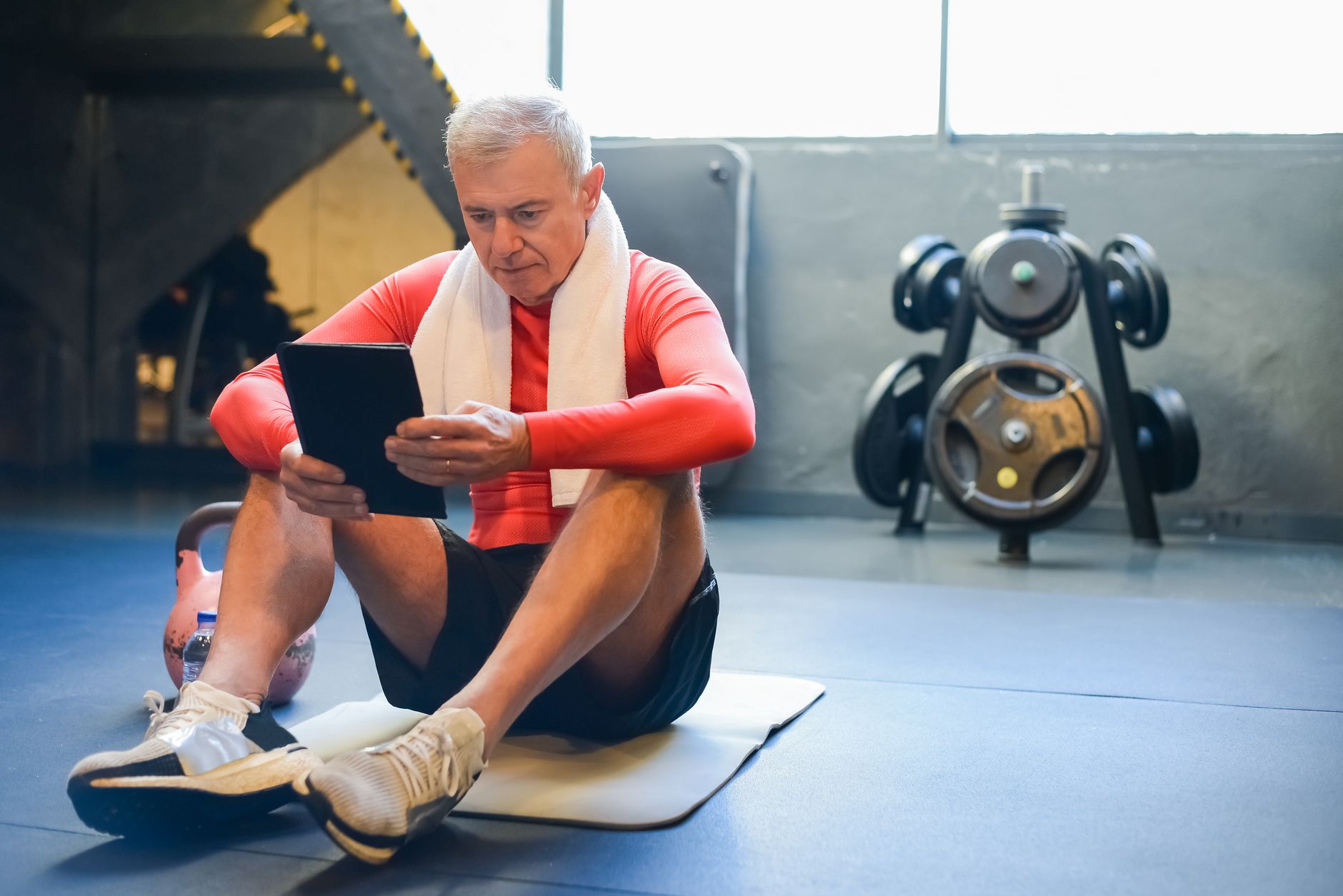 man comparing barbells in gym